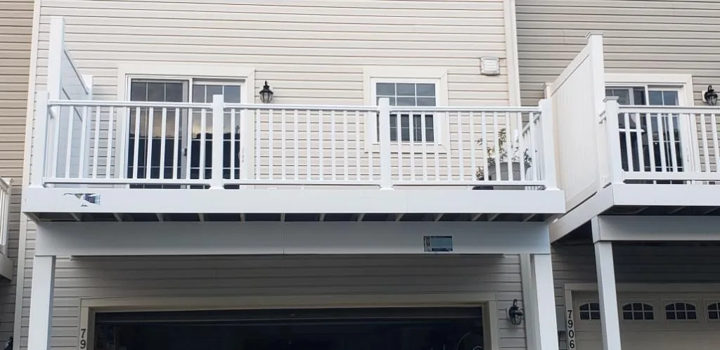 A row of townhomes with white-railed balconies and decks above the garages.
